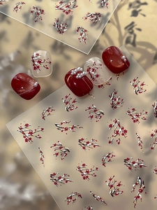 Macro detail of red plum blossom nail art stickers with elegant Chinese style pearl accents