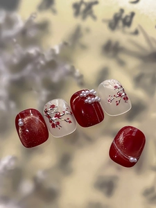 Detail of Chinese style press-on nails with golden plum blossoms and pearl accents