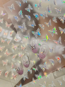 Macro detail of 3D aurora butterfly nail stickers on purple gradient nails with pearls