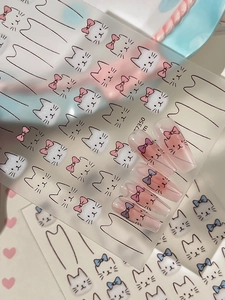 Close-up of cute cat face nail stickers with bowknots applied on transparent long tips