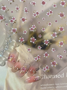 Detailed pink cherry blossom nail stickers with golden outlines on manicured nails