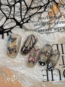 Makro-Detail von Schmetterling-Nagelaufklebern mit Glitzer und Metallstern-Anhängern