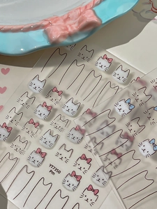 Detail of cute cat face nail art stickers with pink bows and cartoon line patterns