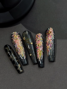 Detailed view of long coffin nails with black glitter, hand-painted fireworks and pearls