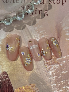 Close-up of pink press-on nails with blue and white porcelain pattern and gold lines