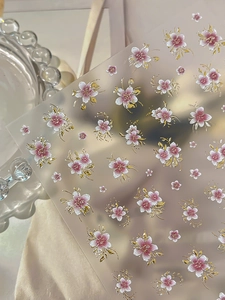 Macro detail of 5-petal floral nail stickers with gold embossed edges and pink gradient