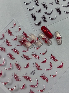 Close-up of butterfly nail stickers in red and black with decorative rhinestones