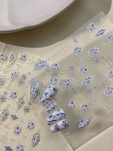 Detail of blue floral and gold geometric nail stickers shown on white display tips