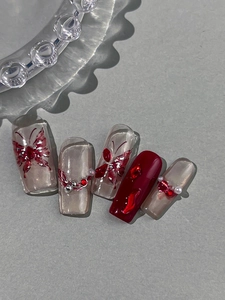 Macro view of five butterfly press-on nails with wine red polish and rhinestone accents