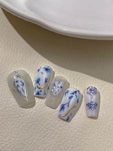 Detail of blue ink flower nail art with silver embossed frames and gold lines