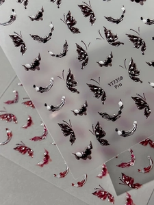 Close-up of 3D butterfly nail stickers in black and red colors with glossy finish