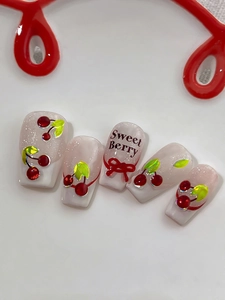 Detail of glittery press-on nails with 3D cherry accents and Sweet Berry text