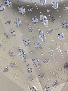 Macro detail of blue porcelain nail art stickers with metallic gold and silver embossing