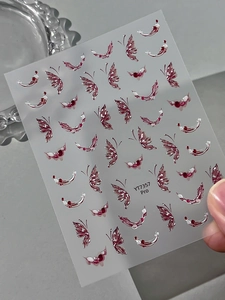 Detailed macro view of 3D embossed butterfly nail art stickers with wine red accents