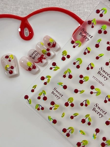 Detail of 3D cherry nail stickers with red bows on elegant white ceramic display
