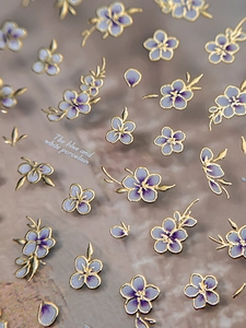 Macro shot of 3D embossed nail art stickers with purple flowers and gold metallic edges