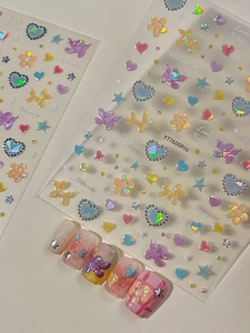 Dettaglio di adesivi 3D per unghie con cani palloncino macaron e finitura laser aurora