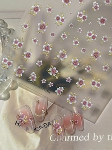 Detail of 3D nail stickers featuring pink floral patterns with elegant gold foil accents