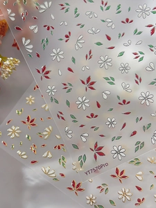 Detail showing 3D embossed floral nail stickers with silver outline and red daisy patterns
