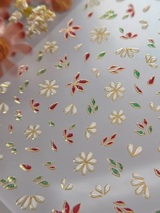 Detail of floral nail stickers with gold embossing and wine red petals on a macro view