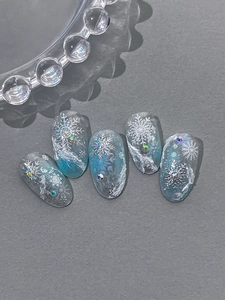 Détail macro d'ongles dégradés bleu et blanc avec des flocons 3D et des strass brillants