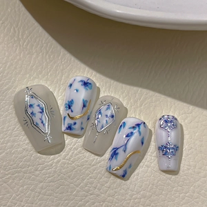 Blue floral porcelain style press-on nails with silver diamond and gold line patterns