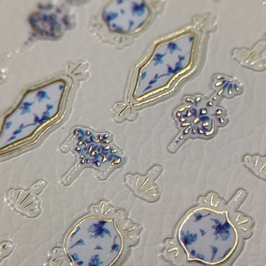 Blue floral porcelain style nail stickers with gold embossed edges on white leather