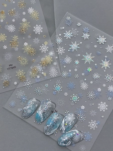Vue détaillée d'autocollants pour ongles flocon de neige sur un fond texturé sombre