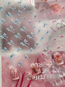 Nahaufnahme von 3D-Schleifen-Nagelstickern mit Kristallen in Rosa und Blautönen