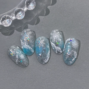 Faux ongles dégradé bleu givré avec flocons de neige en relief et strass scintillants