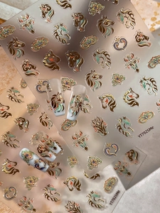 Detail of embossed metal nail stickers featuring horse patterns and hearts in bronze gold