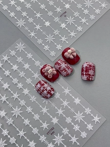 Macro view of white snowflake nail decals with luxury 3D bear and floral accessories