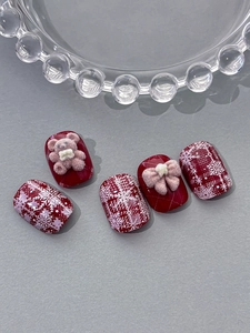 Detailed view of red snowflake nail tips with 3D flocking bear and bow decorations