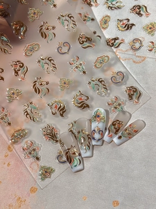 Close-up of Year of the Horse nail stickers with golden horse heads and floral patterns