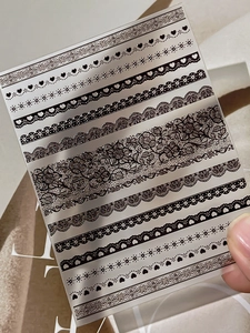Dettaglio di adesivi per nail art con pizzo nero e cuori su pellicola trasparente