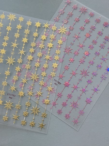 Close-up of snowflake chain nail stickers in gold and iridescent pink laser textures