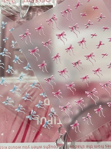 Makro-Detail von 3D-Schleifen-Nagelstickern mit Strasssteinen in Pink und Blau