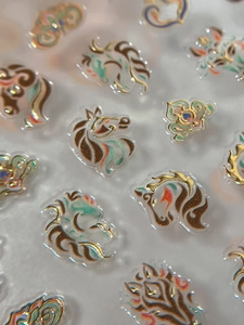Macro detail of 3D embossed nail stickers featuring golden horse heads and floral patterns
