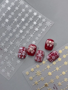 Close-up of red festive nails with snowflake decals, 3D plush bows and a pink teddy bear