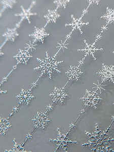 Macro shot of silver metallic snowflake chains for festive nail art decoration