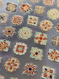 Makroaufnahme von böhmischen Emaille-Nagelaufklebern mit Mandala-Mustern und Goldfolie