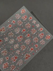 Vue macro détaillée de stickers 3D pour ongles motif feux d'artifice rouge et doré