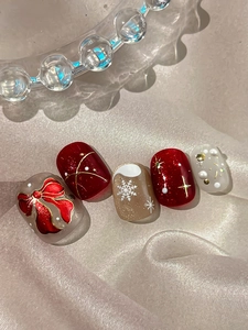 Close-up of 3D Christmas nail art with red bows, snowflakes and pearl accents
