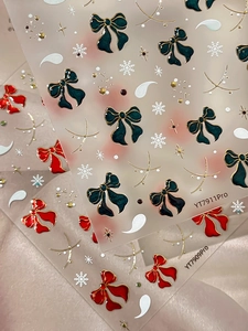 Macro view of 3D bow nail stickers with gold edges in red and dark green shades