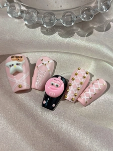 Détail de faux ongles roses et noirs avec breloques 3D et motifs de rubans de ballet
