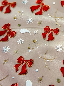 Macro shot of 3D Christmas nail art stickers featuring red bows and white snowflakes