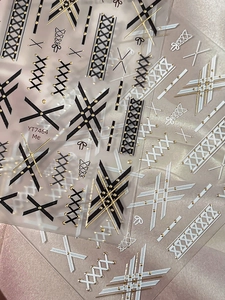 Détail macro de stickers pour ongles à nœuds et motifs grillagés noir blanc et or