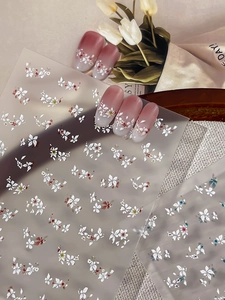 Detail of floral nail stickers with white flowers and red hearts on gradient pink nails