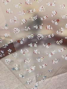 Detailed macro view of 3D embossed floral nail stickers with tiny white flower patterns