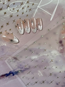 Detailed view of silver starburst and cross nail stickers on French manicure tips